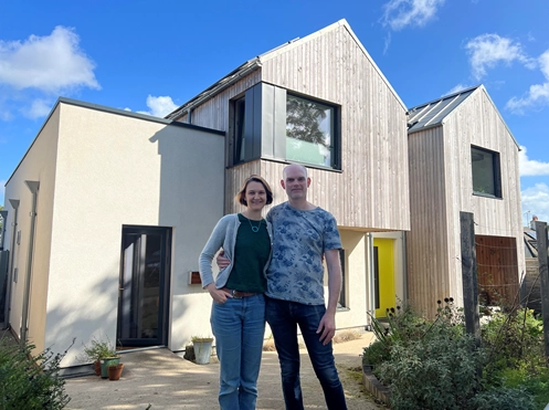 Image of two people standing in front of their house